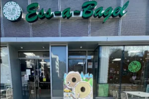 Front entrance of Ess-A-Bagel shop in New York with signboard and bagel cutout display.